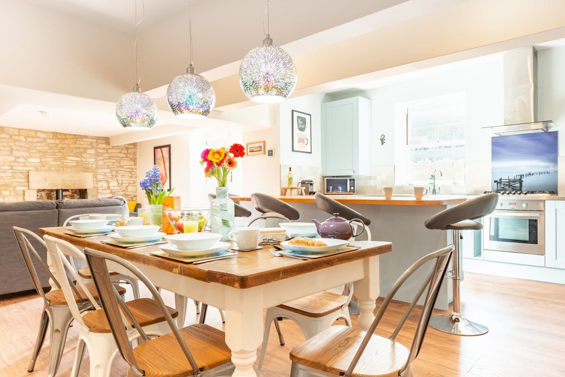 Open-plan downstairs: dining table, breakfast bar and sitting area with the stone fireplace