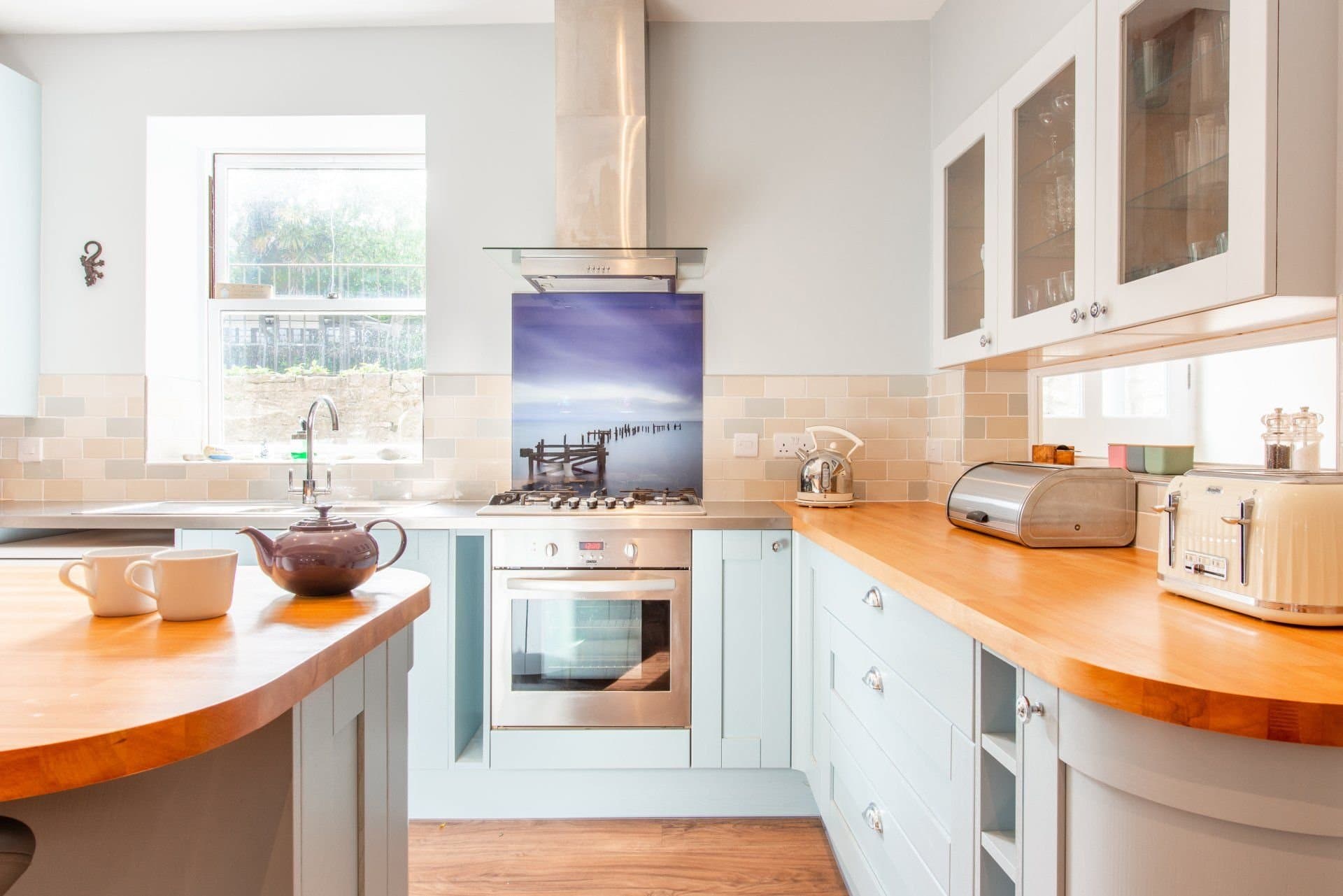 Kitchen with pale blue cabinets, wooden worktops and a breakfast bar