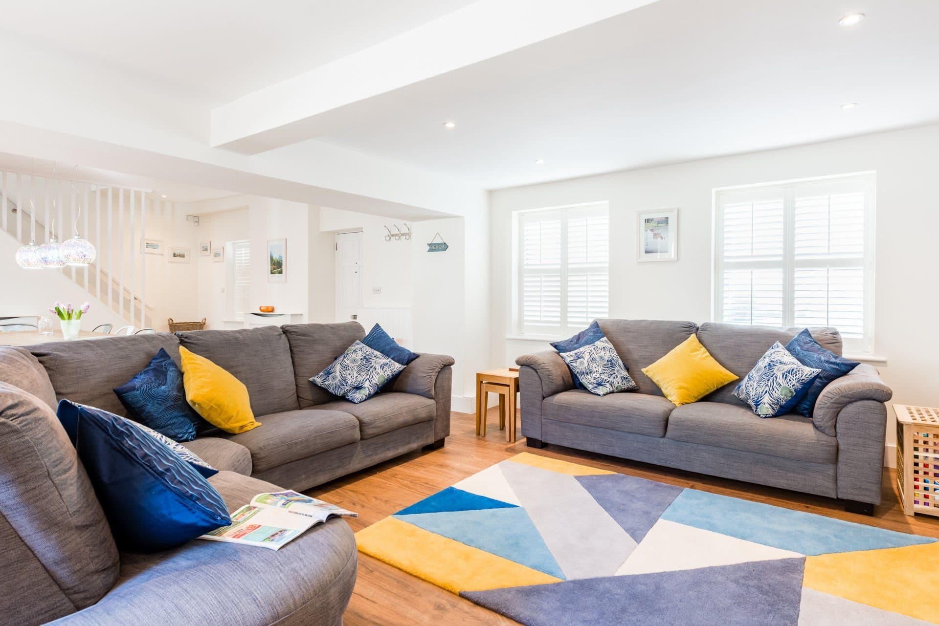 Sitting area with grey sofas, shutters and a view through to the dining table