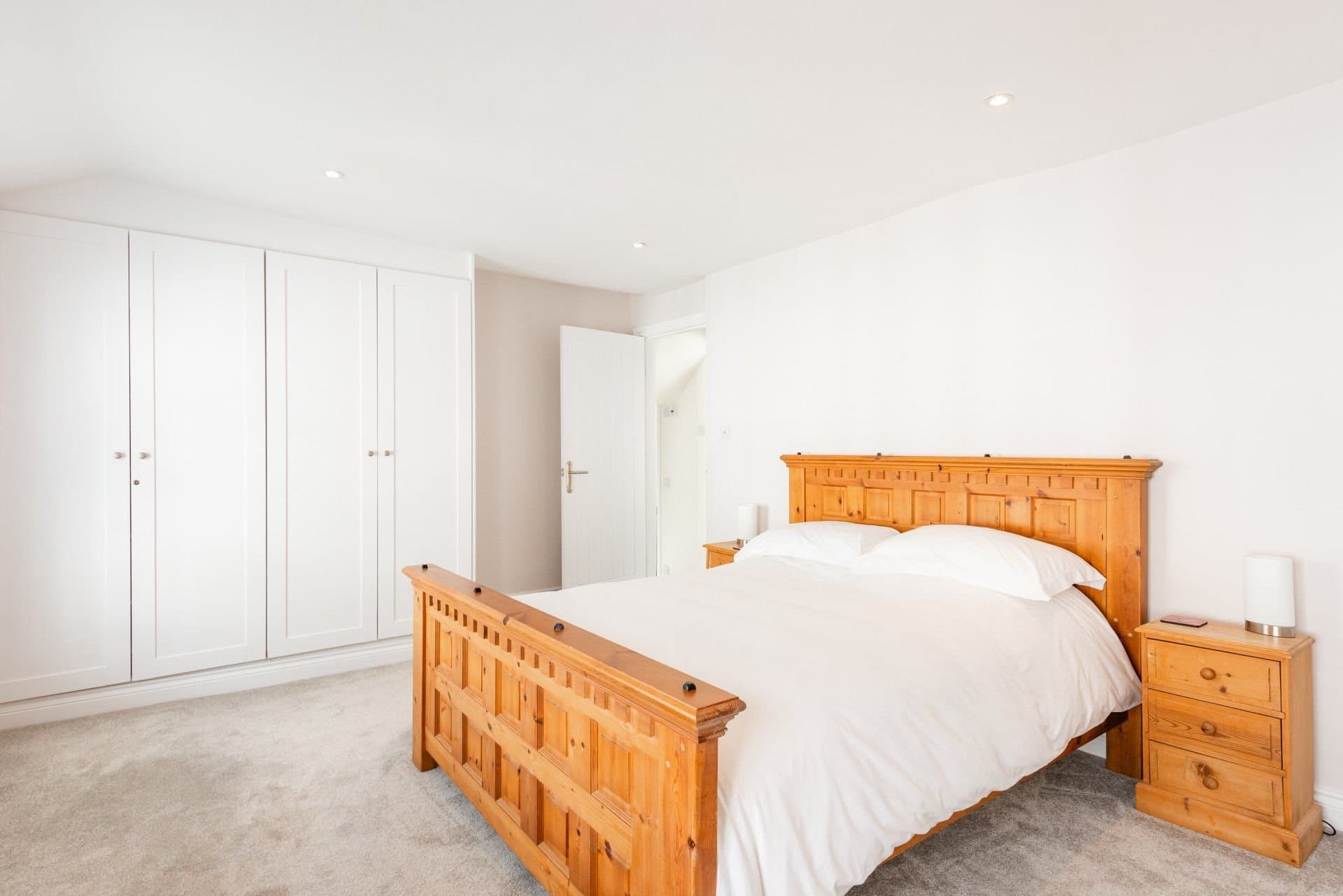Bedroom with wooden bed, bedside tables and a built-in wardrobe