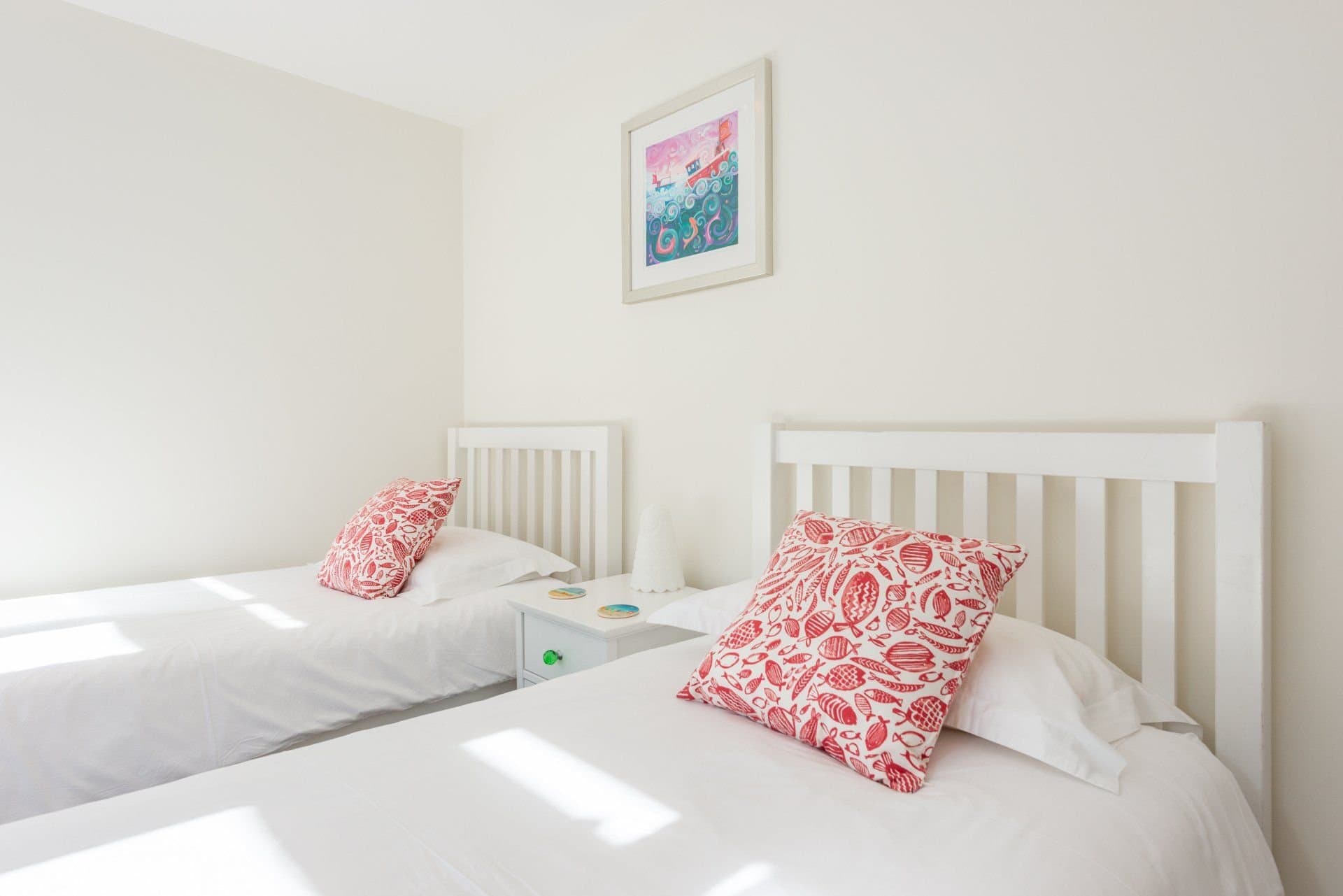 Twin bedroom with white beds and seaside cushions