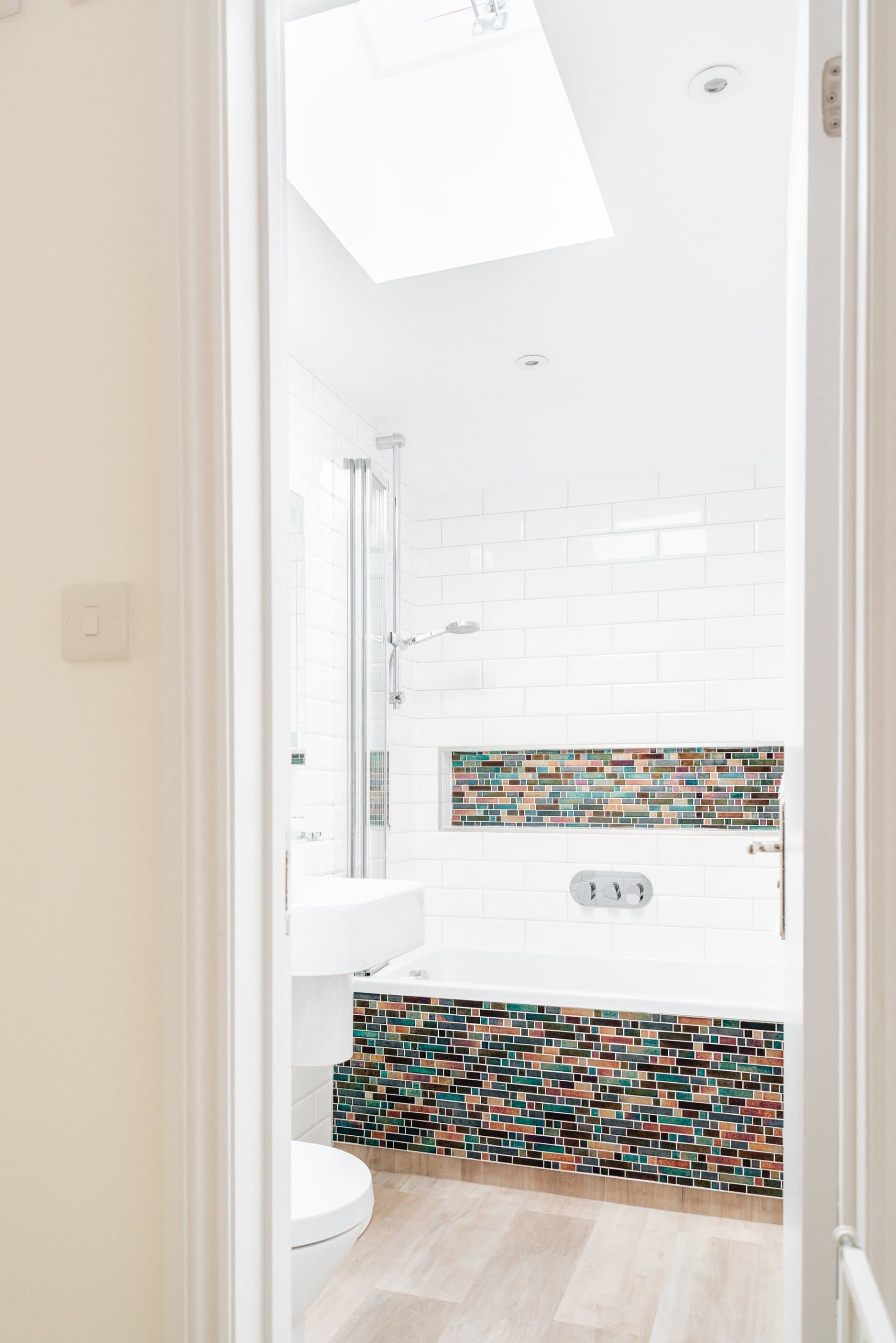 Bathroom with a bath, shower above, mosaic tiles and a skylight