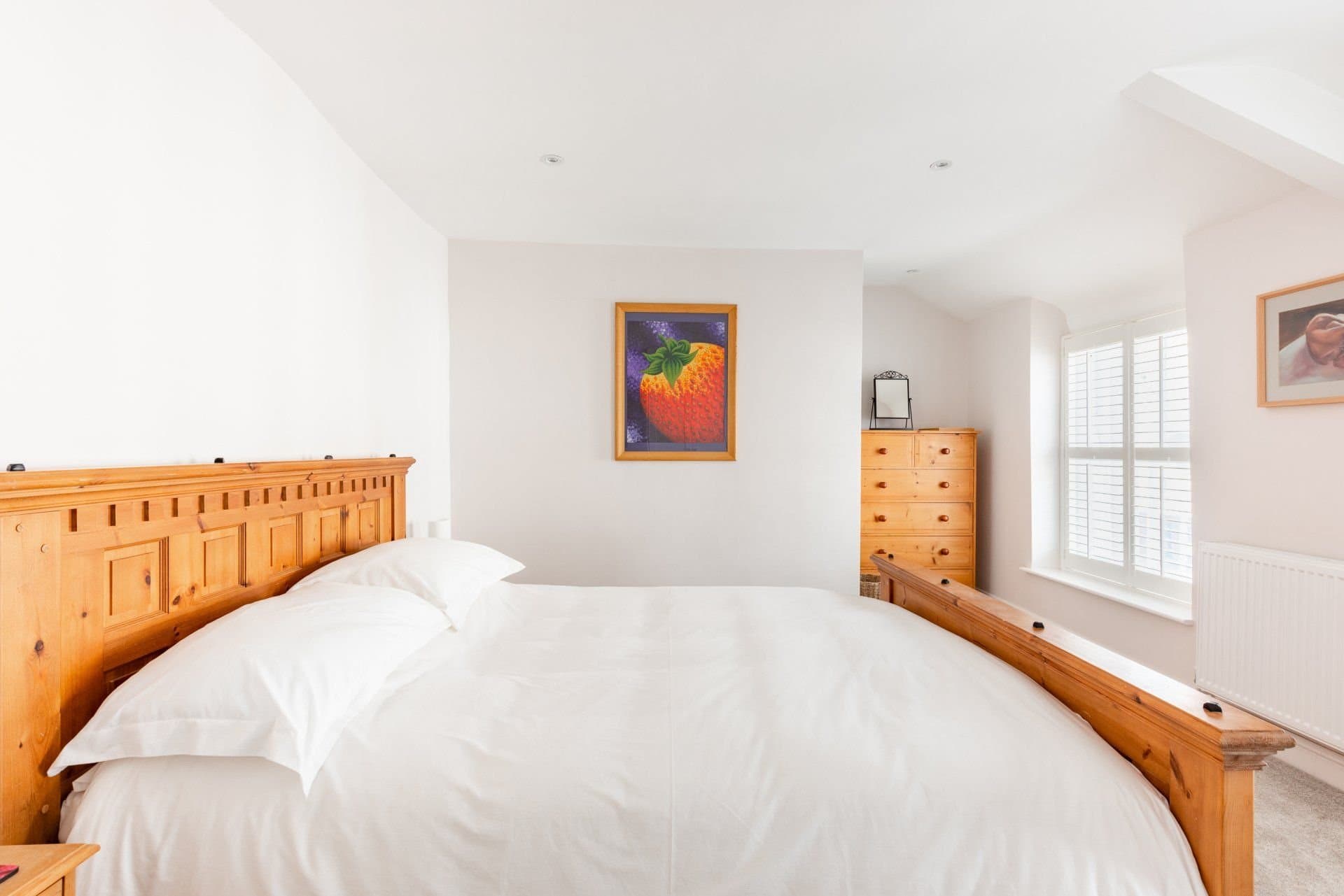 Bedroom with a wooden bed, white linen and plantation shutters
