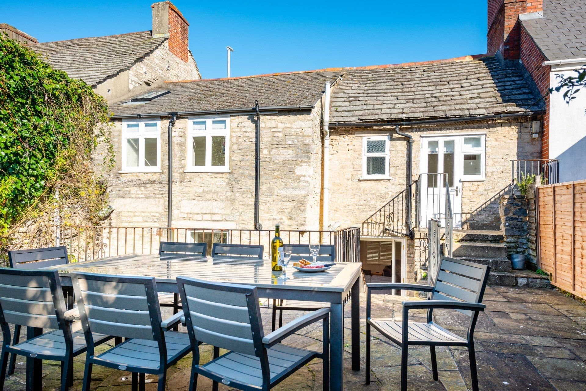 Large patio dining table and chairs against the stone cottage